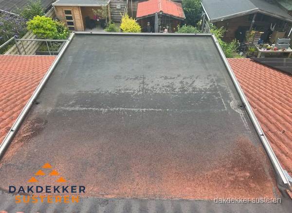 Verouderd plat dak met slijtage tussen schuine daken in Susteren Verouderd plat dak met slijtage tussen schuine daken in Susteren
